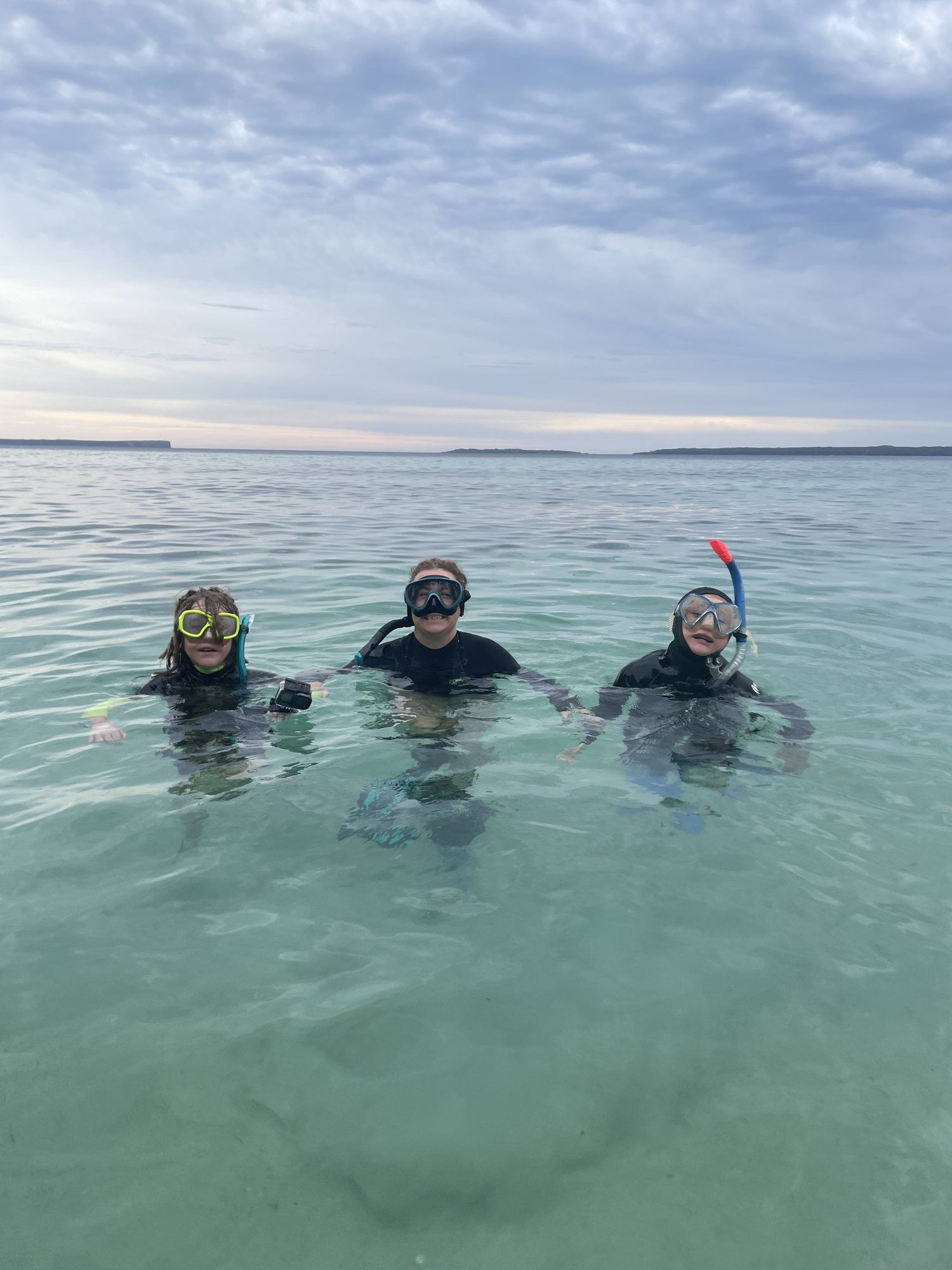 Three snorkellers floating in calm, clear water
